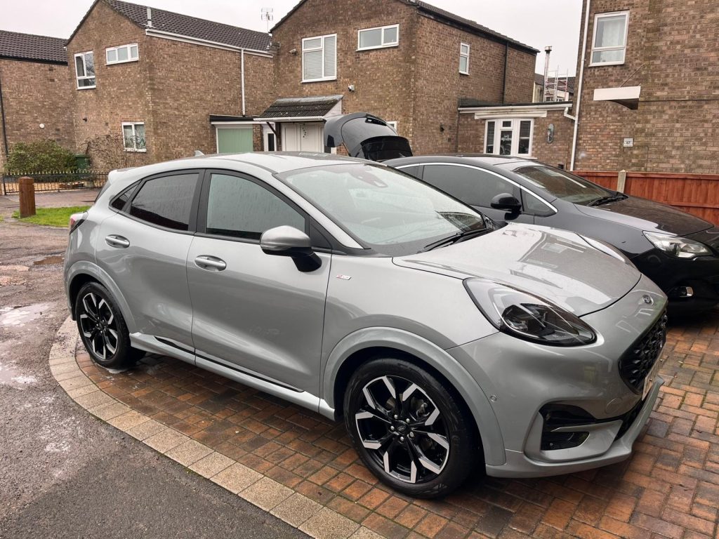 Two cars parked on a driveway sparkling